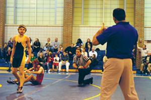COACHING TIME:  Wrestling assistant coach Jeremy Stacy instructs a wrestler during the JV meet on Nov. 22 against Anderson, which was the team’s first match. The team won, and it hopes to build off of the victory. AUDREY COURTER / PHOTO