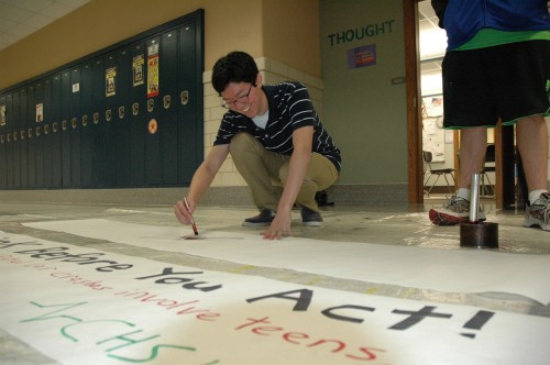 Chris Song, LifeLines member and senior, decorates a poster advertising Red Ribbon Week. This event is week-long campaign to raise awareness of the dangers of drugs and violence. ARUNI RANAWEERA/ PHOTO