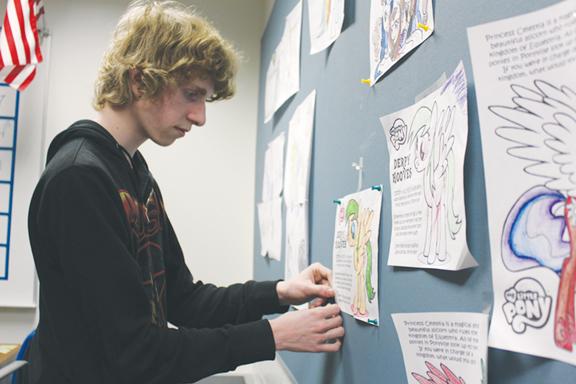 FRIENDSHIP IS MAGIC: Senior Andrew Riley hangs up pictures colored by the My Little Pony Club (MLPC). According to Riley, he formed MLPC after he started watching the show over the summer. JULIE XU / PHOTO