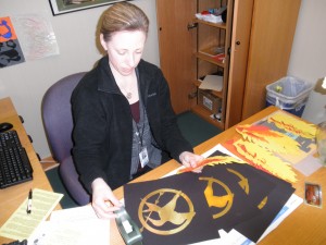 Media manager Carol Schatz lays out the planned decorations for the Hunger Games  promotional event. The media staff will host the event, which involves scavenger hunts and prizes, from March 12 to 21. DAVID CHOE / PHOTO