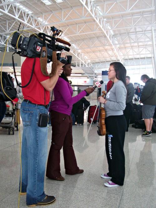 A WishTV reporter interviews Melinda Song, symphony orchestra member and senior, at the Indianapolis International Airport. The orchestra was planning to travel to China for a group trip but had their flight postponed due to weather. Local news stations interviewed the orchestra on their situation. ROCHELLE BRUAL/ PHOTO