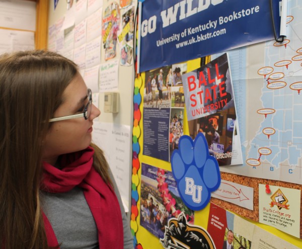 Senior Meredith Wettersten examines the bulletin board in the Advancement Via Individual Determination (AVID) room, which is covered in brochures and flyers from universities. Wettersten said the AVID program helps her find scholarships in order to pay for an increasingly expensive higher education. NIVEDHA MEYYAPPAN / PHOTO