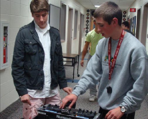 Senior Samuel Pickett (left) instructs another WHJE staff member on using a portable sound system. Along with being a member of WHJE, he is also successful academically.