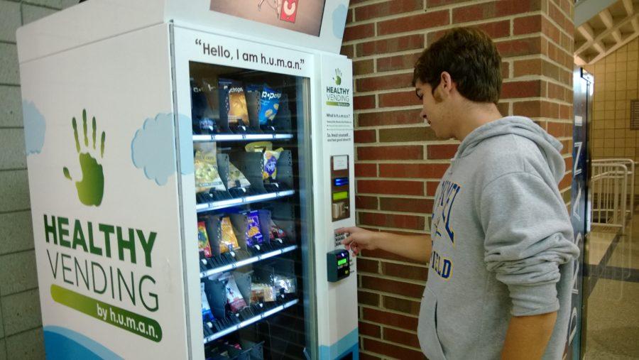 Junior James Holland purchases a snack from one of the new vending machines. The new machines operated during the school day and provided healthier options, unlike the old machines. MICHAEL ZHAO / PHOTO
