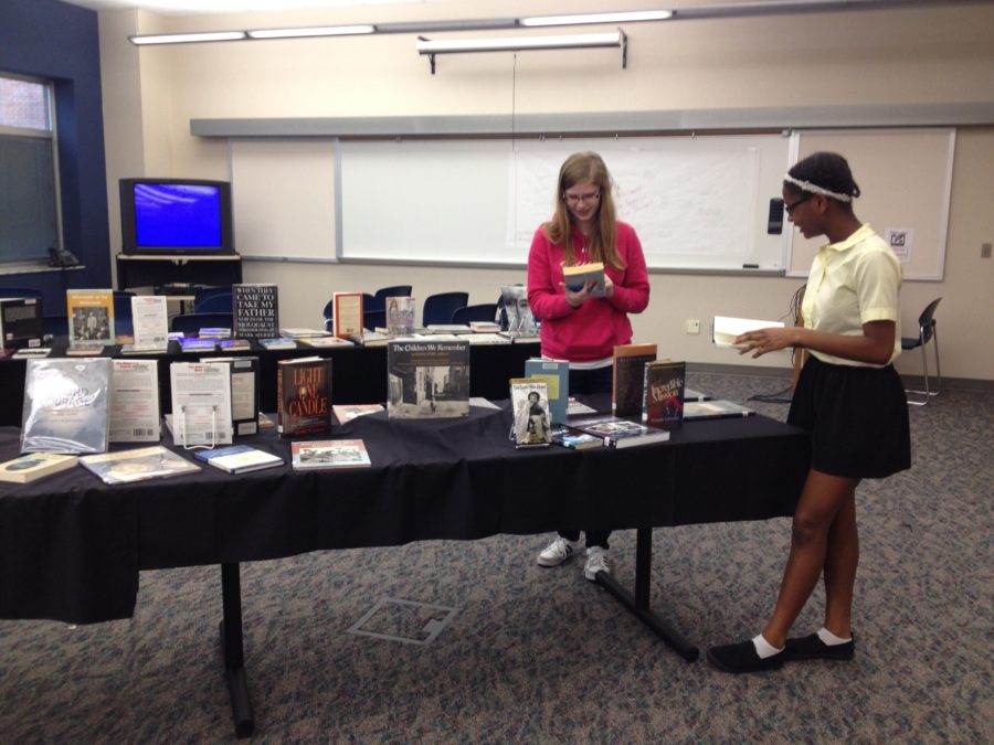 Media aides and sophomores Johanne Vincent and Hannah Stigter look through books in the Holocaust gallery walk. The media center hosted a Gatsby gallery walk as well. JENNY ZHAO/PHOTO