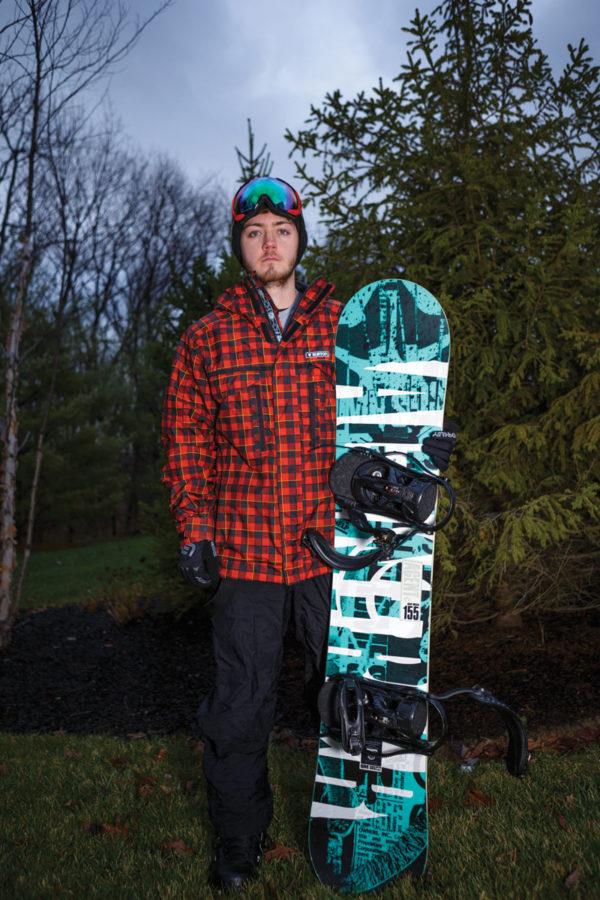 Senior Ben Thatcher holds his snowboard. Thatcher started snowboarding at the age of 10 and said he likes the adrenaline he gets from the sport. 