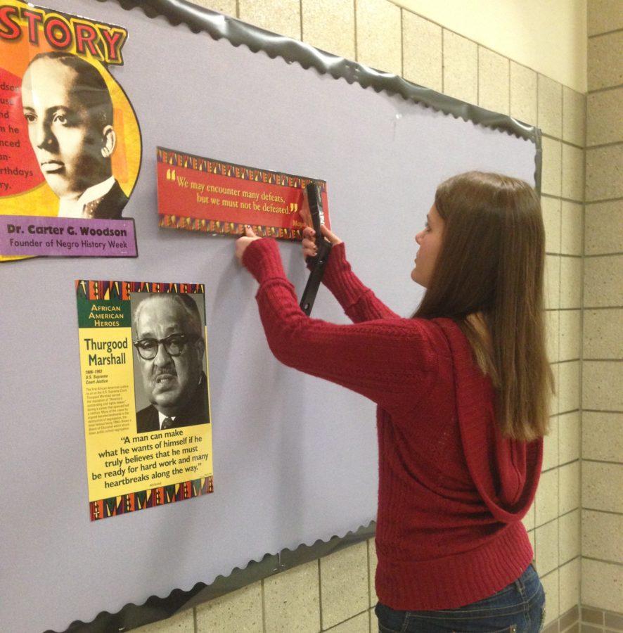 Co-president and senior Sydney Burget puts up the bulletin board for Black History Month. Sponsor Rebekah Overbey said the winning SRT of the trivia contest will receive a prize. CYNTHIA WU / PHOTO