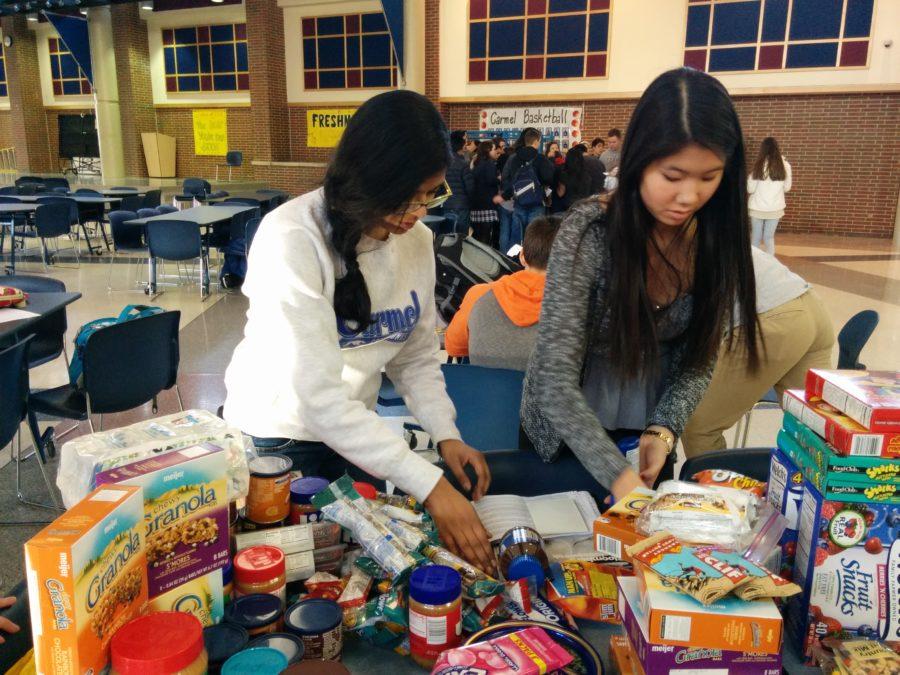 Natasha Crasta, Key Club vice president and senior, and Cynthia Cahya, Key Club secretary and sophomore, pack food for the homeless. Key Club members will vote for a new class board on April 16. MELISSA YAP / PHOTO