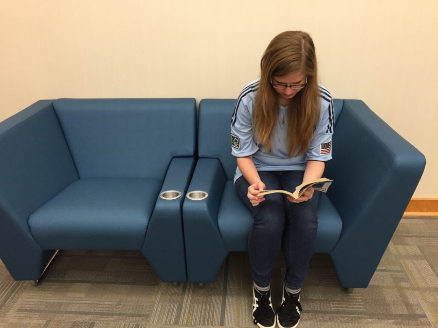 Hannah Stigter, media aide and junior, reads a book in one of the new pieces of furniture at the media center. Almost all of the furniture and carpet in the media center is new.