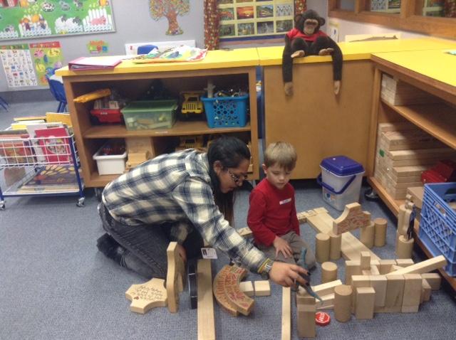 Rosa Alpizar, student teacher for Kids’ Corner and senior, and a preschooler at Kids’ Corner play with toy dinosaurs in a house they built from blocks. Alpizar said that Kids’ Corner has prepared several lessons and activities to teach the preschoolers about colors, numbers and shapes.