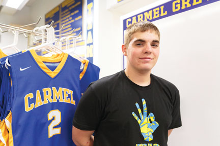Helping hand: Senior Kyle Yost  stands proudly in front of the CHS men’s basketball uniforms. This will be Yost’s fourth year managing the team. 
Kyle Crawford // Photo