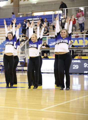 SPIRIT FINGERS: Ally Vaughan, Olivia Smulevitz, and Olivia Robertson (left to right), Coquette dancers and seniors, perform at the women’s basketball game halftime on Dec. 4. The team dances to entertain the crowd and exhibit the talents of its dancers. Mike Johnson // photo