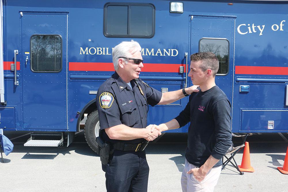 Chief Jim Barlow greets senior Tyler Bickel in front of the Carmel Police Departments Mobile Unit. Barlow said he looks forward to working with both Carmel police and the community as chief.
