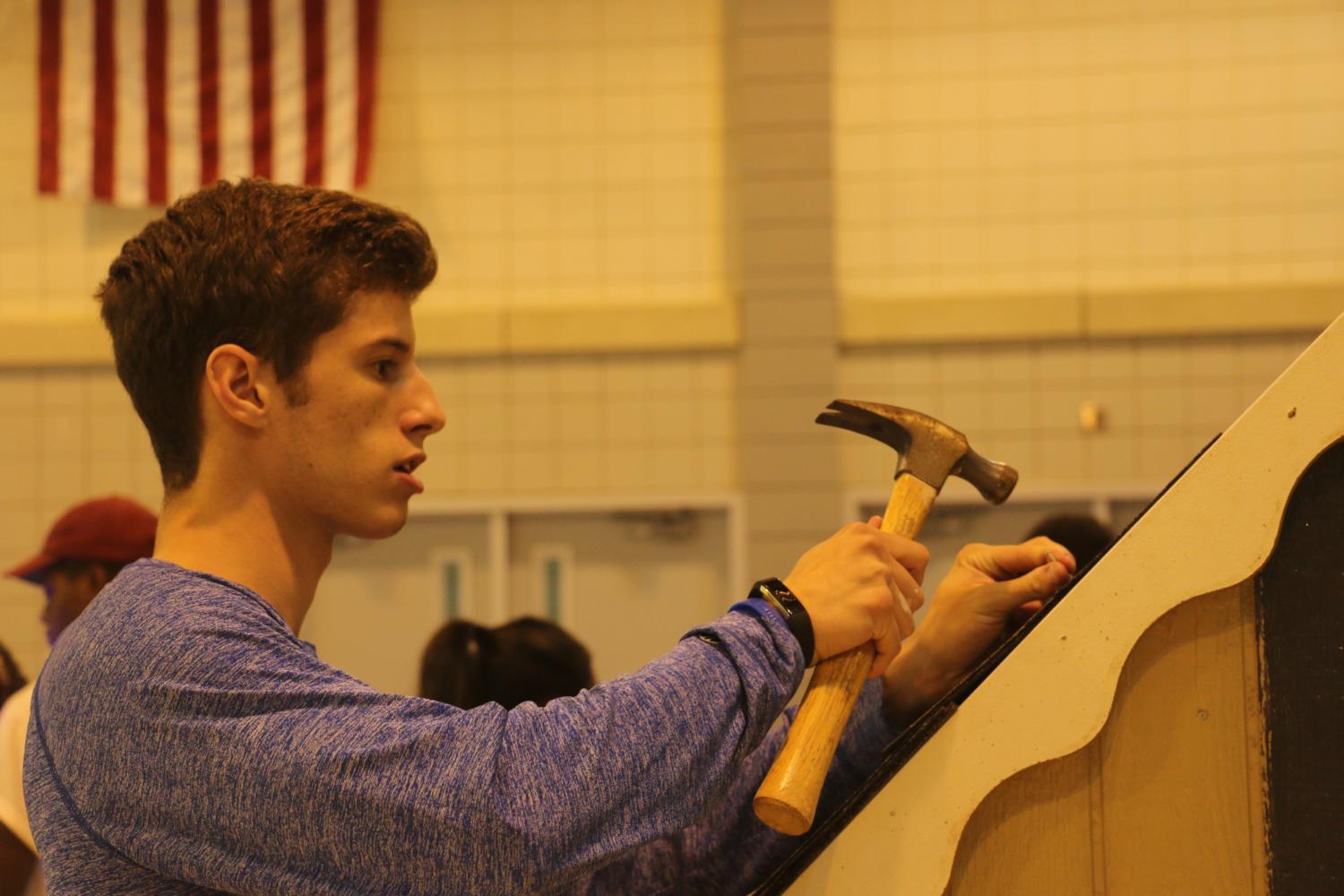 A senior helps to hammer shingles into his grade’s playhouse on Sept. 13 in the fieldhouse. He is able to work quickly, willingly and doing any job that needs to be done. The senior’s “SING!” playhouse is well thought out and made by a great group that works as a team really well.