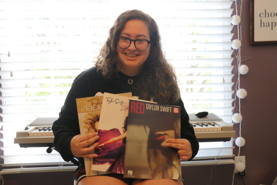 Junior Paige Thompson holds up three piano books of Taylor Swift’s music. Swift published the books to tell the story behind her music. 