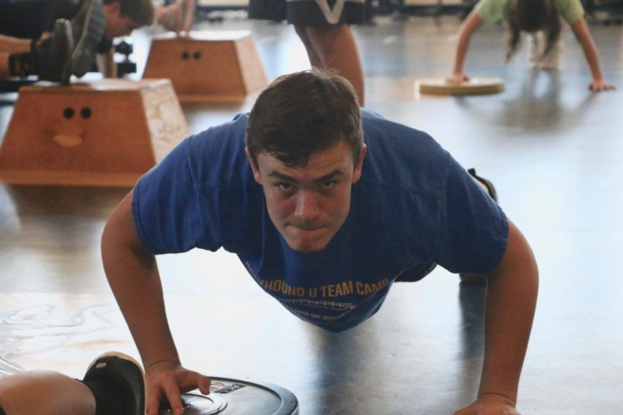 Freshman Bucklin Robbins alternates push-ups with a weight in Advanced Physical Conditioning (APC) on Dec. 1 during third block. Robbins played football for the freshman team this past season, and it was his first time in APC.