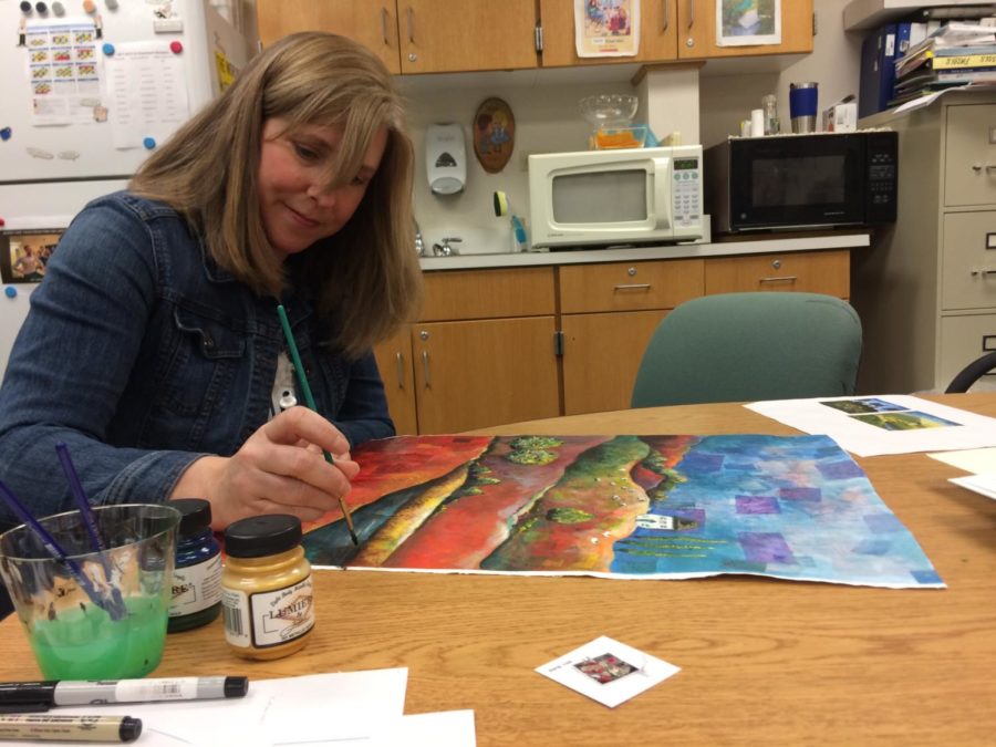 National Art Honor Society (NAHS) sponsor Jennifer Bubp finishes a painting for an art show at Soho Cafe, which took place on March 1. NAHS will host an event on March 29 to raise money for charity.