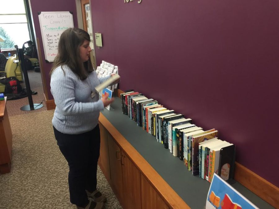 Jamie Beckman, young adult section librarian, arranges books, which are prizes of an upcoming winter reading program. This is the second year that the library will host a winter reading program.