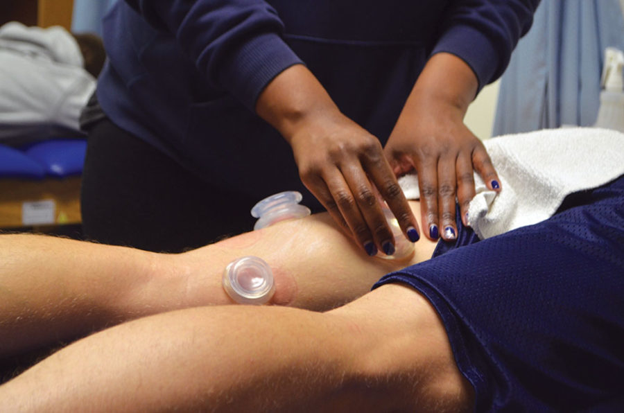 RELAX AND RECOVER:
Spencer Gudgel, track athlete and senior, receives cupping therapy from certified athletic trainer Brittani Moore. Gudgel said cupping releases muscular stress by stimulating blood vessels, allowing for better blood flow. 
Sam Shi | Photo