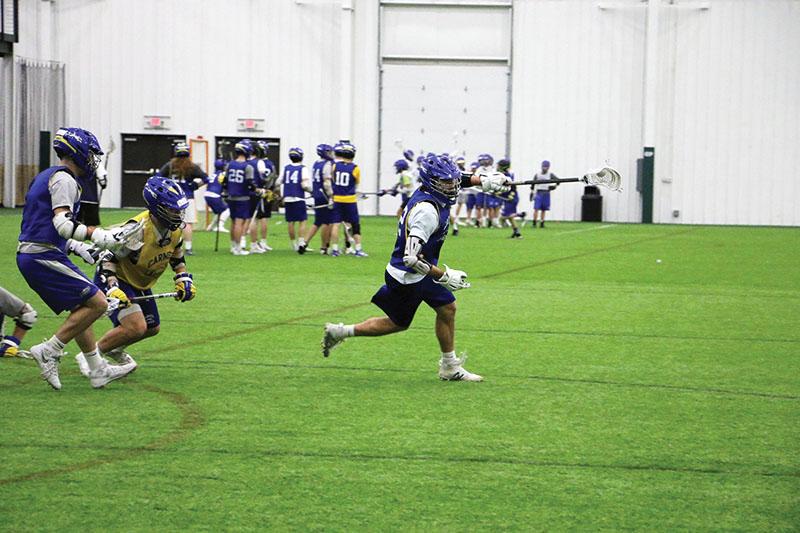 TEAM WORK:
Mark Allen, varsity lacrosse player and senior, clears the ball out during a drill at practice. The team practices game-like scenarios to sharpen their skills on the field come competition.
