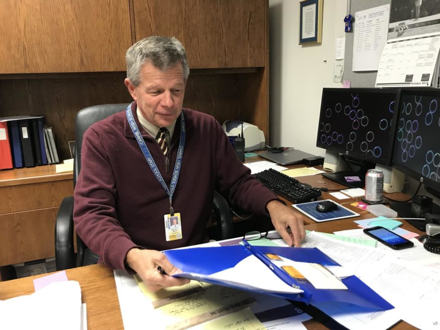 Bruce Wolf, Champions Together co-sponsor and assistant athletic director, reaches for his glasses as he looks through athletic awards. The club will host a Unified Basketball and Cheer Clinic Dec. 7.