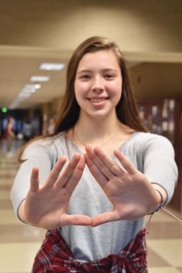 THEORY TIME: Senior Olivia Krall makes the illuminati symbol with her hands for a photo. According to Krall, she started Conspiracy Theory Club after visiting the Denver airport. 