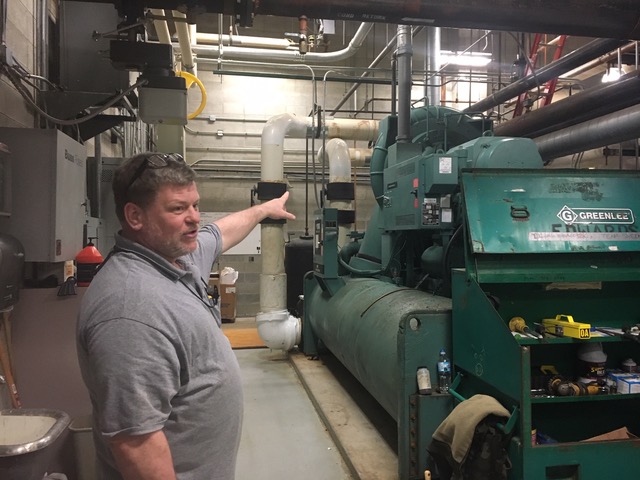 Maintenance worker Fred Napier points to one of the school’s boilers. The maintenance department is currently working on preparing the school’s coolers for the upcoming warmer weather and they have an outside company helping them.