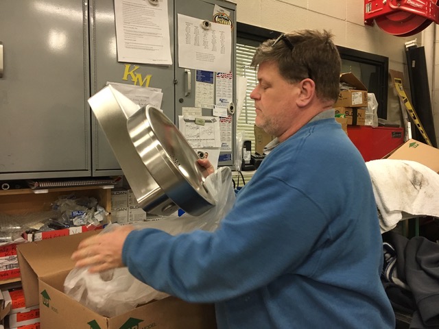 Maintenance worker Fred Napier holds a new water fountain that he will use to replace a water fountain that has broken. This is one of many routine tasks that the maintenance staff does to keep everything running smoothly.