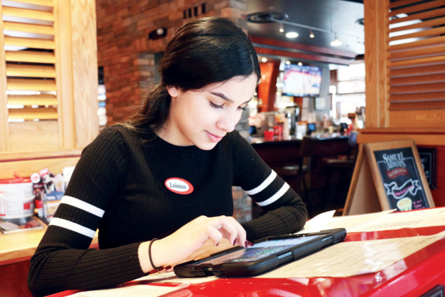 MAKING MONEY: Senior Luisana Rodriguez checks how many seats are available in Red Robin. Rodriguez has worked at Red Robin for a little less than a year. She said that her family sends money over to their relatives in Venezuela to help make their lives easier.