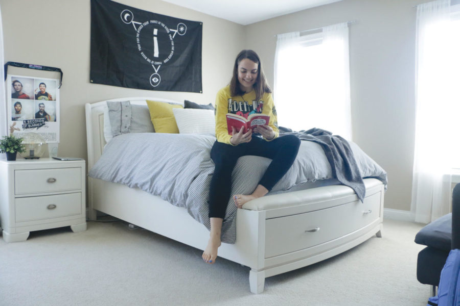Sophomore Ashley Elmore reads a book in her room. Elmore said she makes use of shelves around her room to store her books and other belongings so she always knows where they are.