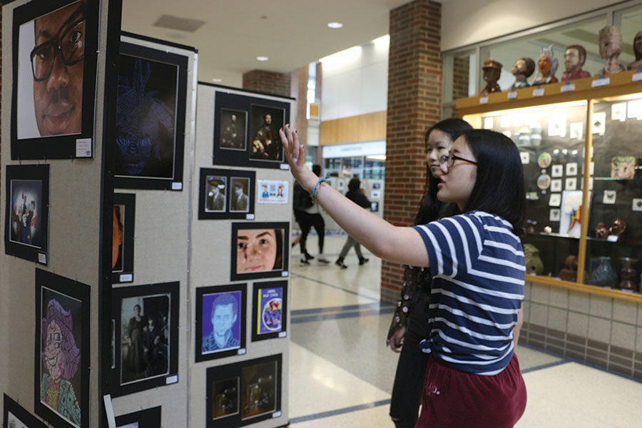 Senior Jessica Qu and junior Minjeong Kim point at a particular piece of artwork. Qu said she applied for a curator position because she is interested in art and design.