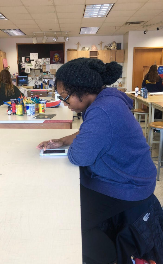 NAHS member and senior Destiny Hall looks at art-themed parties on her phone to brainstorm ideas with her fellow committee members.