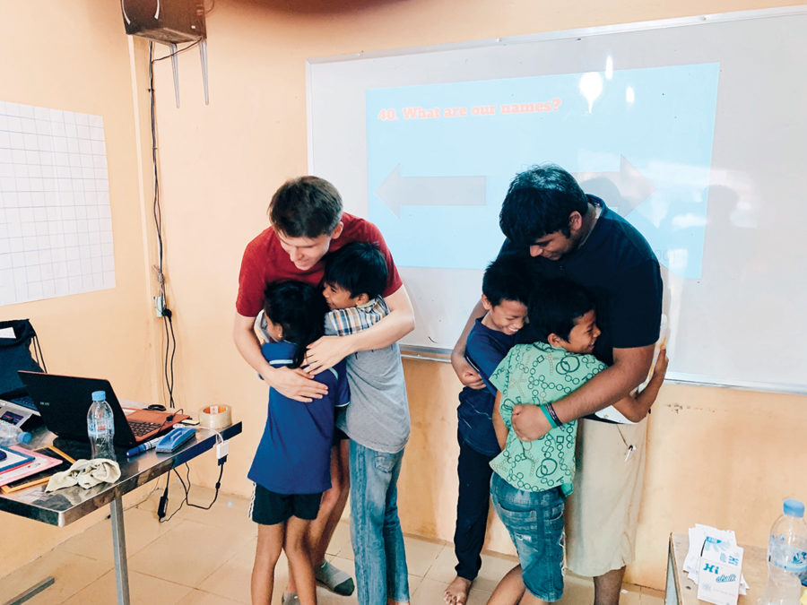 Senior William “Will” Pugh (left) hugs two Cambodian students. Pugh said his involvement in the TASSEL club to help others has had a positive influence on him.