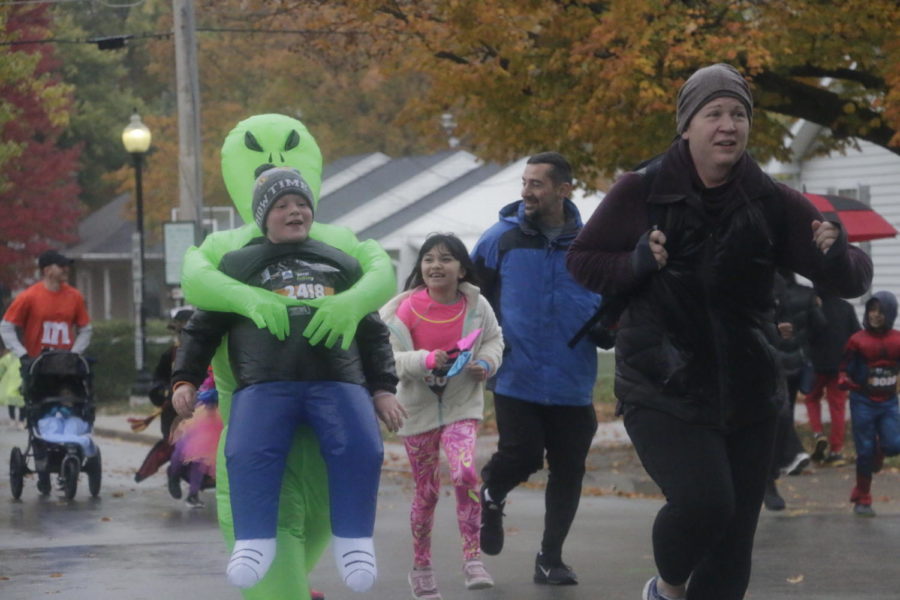  Costumed runners come close to the finish line of the 5k race as volunteers and supporters cheer on the sidewalk. Although the race was held on the rainy Saturday morning of Oct. 26. 2,500 participants attended to support the Carmel Education Foundation.