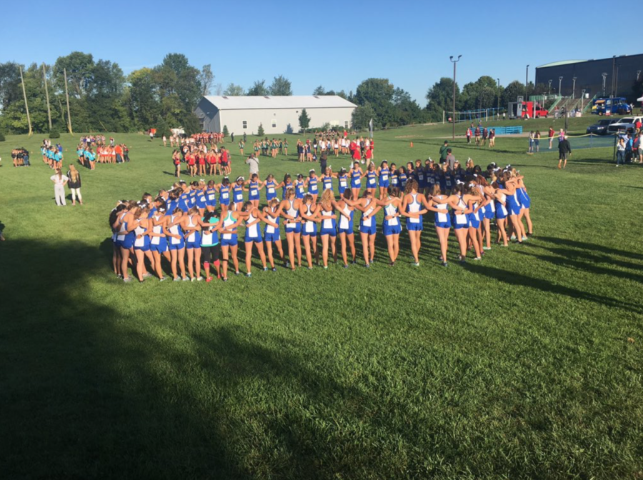 The varsity team huddles up prior to a home meet. “We are looking forward to the rest of the season and hopefully can win a State championship this fall,” varsity runner and senior Phoebe Bates said.