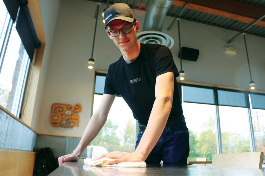 Ben Ring, Chipotle employee and senior, wipes down a table during one of his shifts at Chipotle. Ring said cleaning up is one of the responsibilities he has as a worker for Chipotle. 