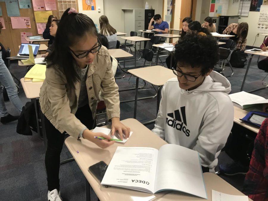 Melissa Su, chief of role plays and junior, works with a student during SRT regarding DECA district exams. Su said students should take practice tests in order to prepare for the exams. 