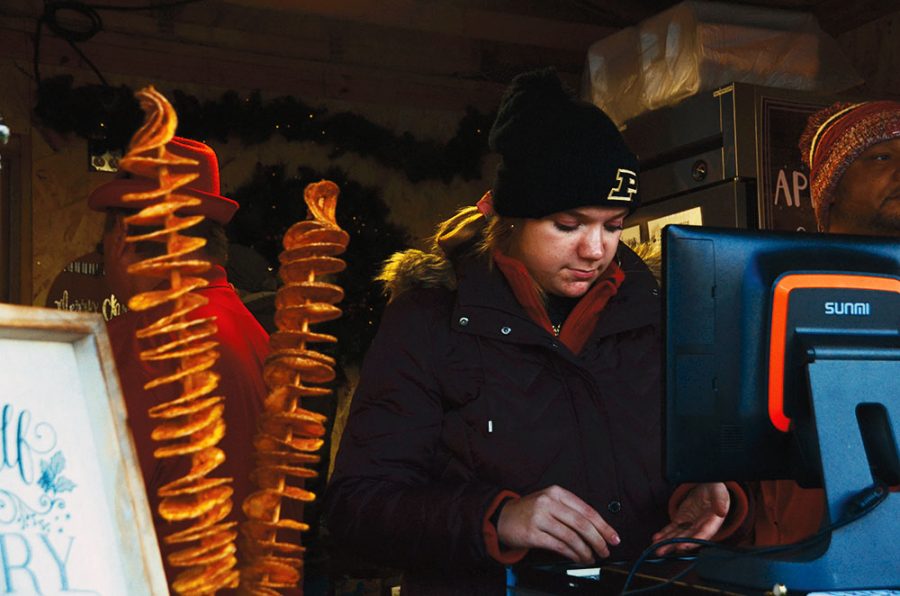 An employee opens the cash register at a German food stand that sells food such as kartoffel spies, a deep-fried and spiral-cut potato which is a popular German street food. This stand can be found at the 
Carmel Christkindlmarkt.