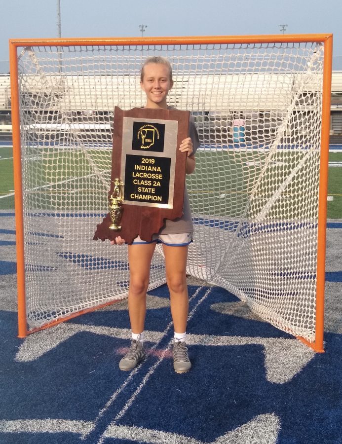 Jillian Schlieper, womens lacrosse player and senior, poses with the State trophy after the game last season. Schlieper said she was disappointed that the spring season was cut short since she was hoping to win three straight State titles in a row. 