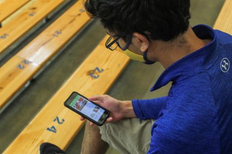 Senior Neal Joshi plays fantasy football on his phone while sitting in the varsity gym. Fantasy football has greatly increased popularity over the past few years and has caused more interest in the NFL.