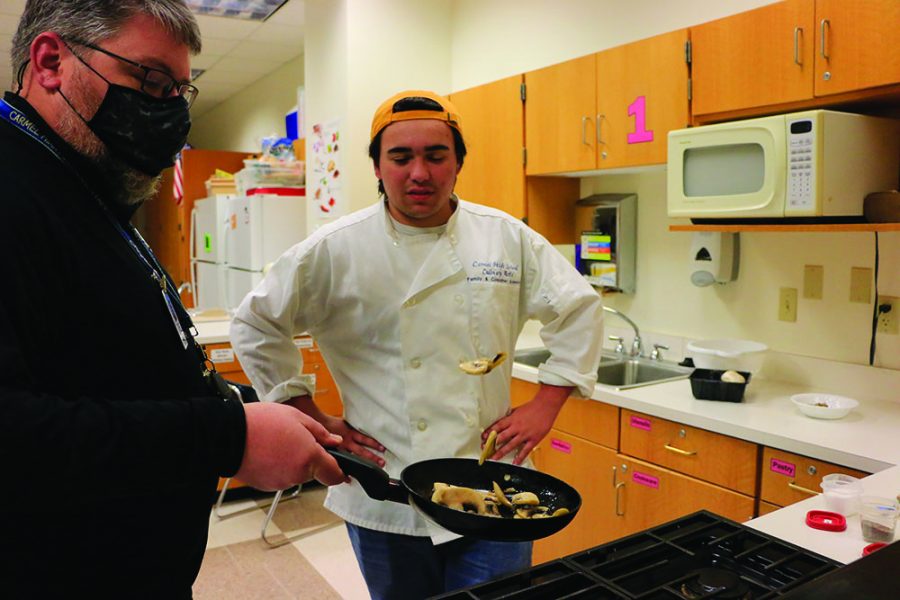 Cooking teacher Nicholas Carter demonstrates how to toss mushrooms to senior Matt Arnold. He tells Arnold to have confidence in cooking.