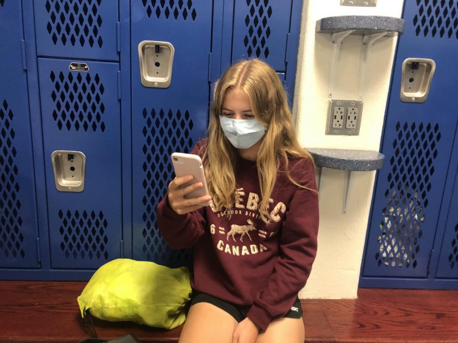 Savannah Hill, cross-country runner and senior, reads a team email before practice. Hill said she has high expectations for the tournament season.  