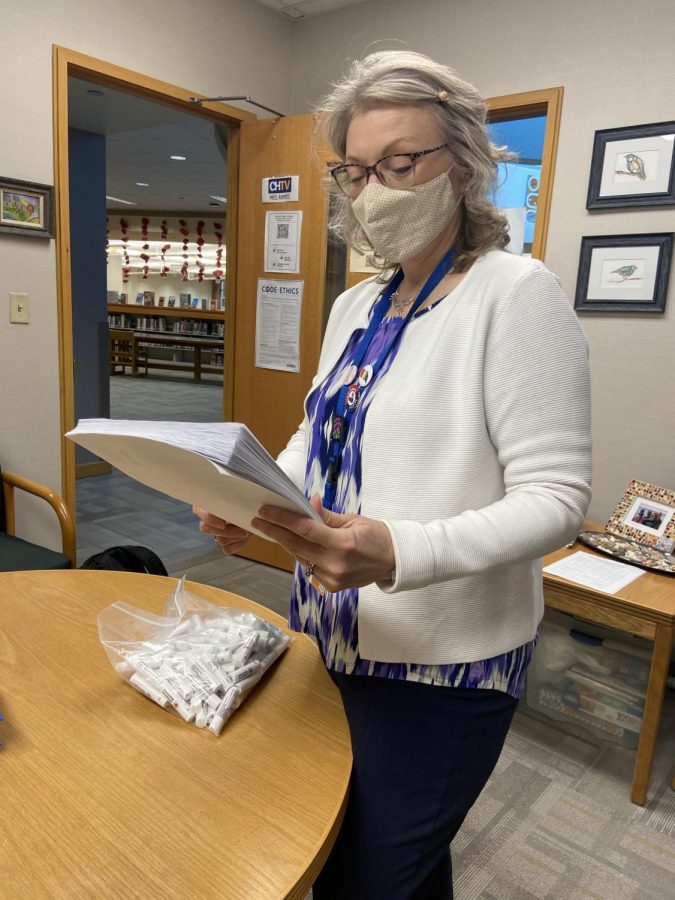 Terri Ramos, media center and communications department chairperson, reviews worksheets for the Red Cross water safety lessons. She will be distributing prizes to randomly selected students who completed the whole sheet correctly.