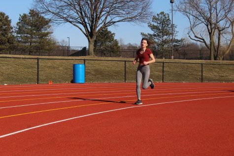 WARMING UP: 
Lily Rose, varsity women's track and field team member and junior, runs a lap as a part of her  warmup. Rose said she thinks cross country has developed a supportive culture to help any girls who may be struggling with body image issues.