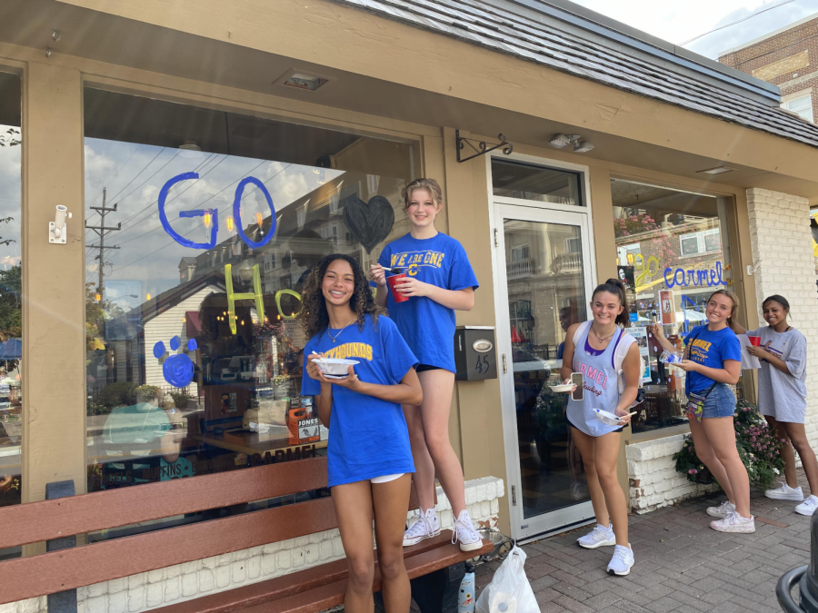The+cheerleading+team+paints+storefronts+in+Carmel+downtown+as+part+of+their+preparations+for+homecoming+week.+Brooke+Kibler%2C+head+coach+of+competition+and+football+cheer%2C+said+the+cheerleaders+spend+several+hours+painting+storefronts+to+raise+homecoming+spirit+for+the+football+game+on+Sept.+24.