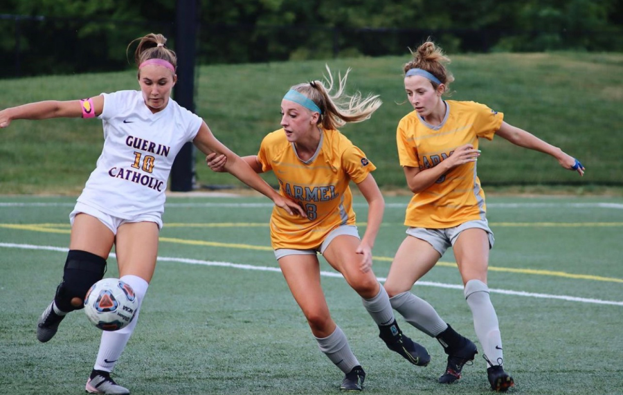 Kathryn Hartung (center), defensive center midfielder and junior, defends against an opposing player in a game against Guerin Catholic on Aug. 20. Hartung said she frequently works on communication with fellow defensive players on the team to make sure the team concedes very few goals.