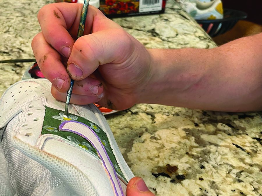 artful strokes: 
Senior Nash Cheslock adds details to a pair of white Nike Air Force 1 shoes. Cheslock said he mostly uses acrylic paints for these projects.