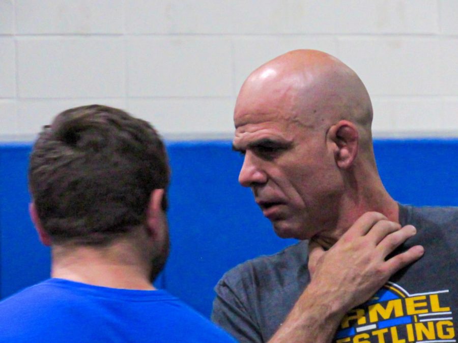 Head Coach Ed Pendoski (right) talks to another coach during practice. Pendoski said the common image of wrestlers changing their weight to drop down to a lower weight class is largely a myth. 