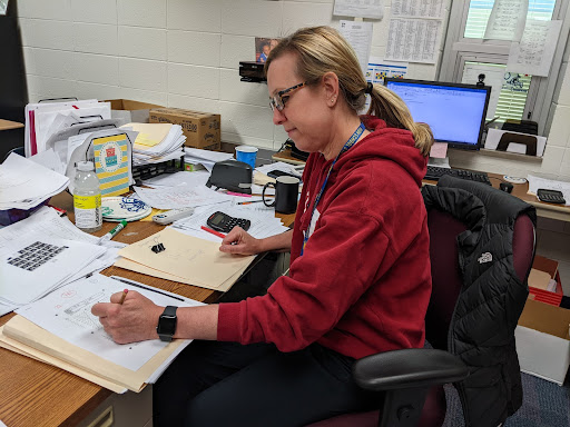 Michelle Foutz, club sponsor and economics teacher, grades economics tests that students take independently to study.