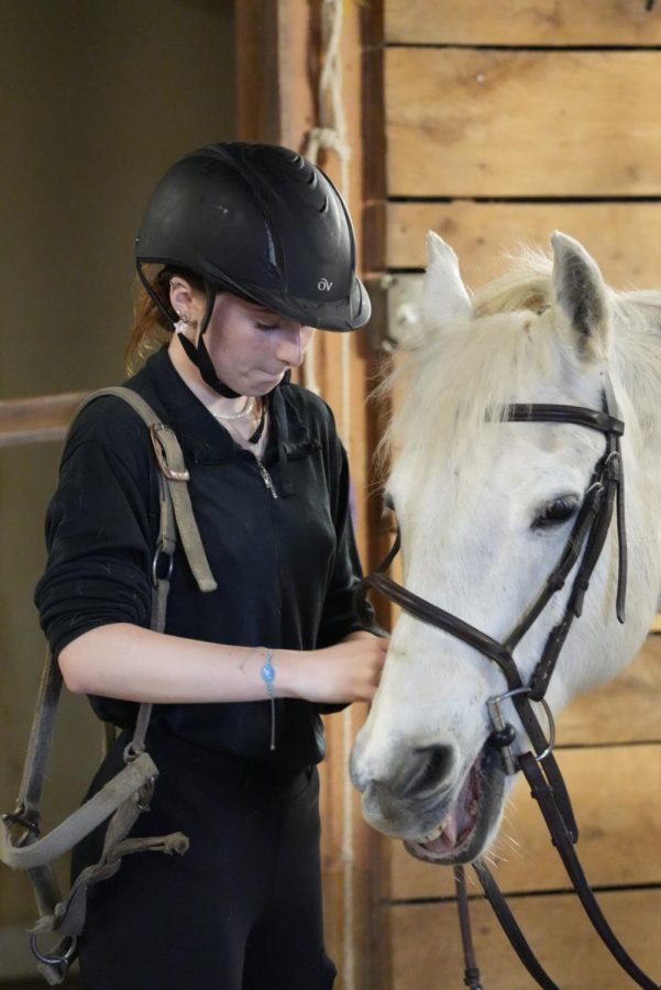 Sage Moore, horseback rider and senior, cares for her horse after riding. Moore said that although she thinks some horse betting is unethical, most horse betting is ethical as long as individuals involved in betting complete their research on the race and are aware of the rules involved to ensure safety.